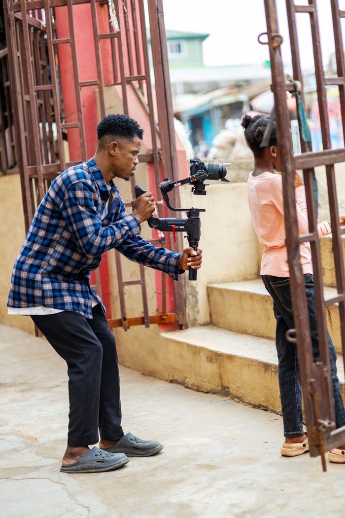 A director focuses on capturing a scene outdoors using a gimbal-mounted camera.