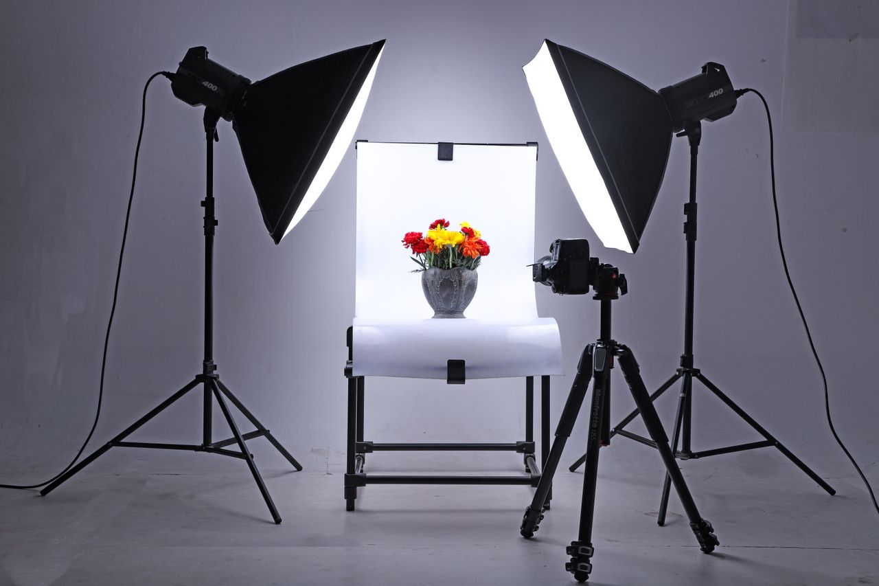 Studio setup with lights and camera capturing flowers in a vase, ideal for product photography.